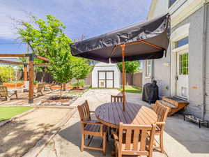 Fenced backyard featuring outdoor dining space, a patio area, a storage shed, and a grill