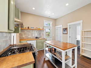 Kitchen featuring open shelves, green cabinets, decorative backsplash, dark wood-style flooring, and recessed lighting
