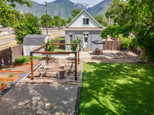 Rear view of property featuring a fenced backyard, a patio area, a deck with mountain view, an outdoor structure, and a garden