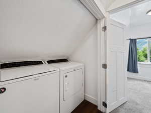 Laundry room featuring a textured ceiling, washer and dryer, and dark carpet