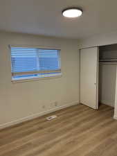 Unfurnished bedroom with light wood-style floors and a closet