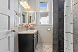 Full bathroom featuring vanity, light tile patterned floors, and a shower with shower curtain