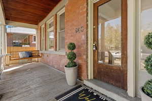 View of exterior entry featuring brick siding and covered porch