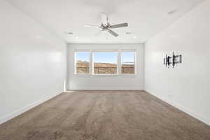 Spare room featuring light colored carpet and a ceiling fan