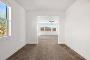 Empty room featuring dark carpet and baseboards