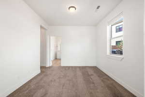 Spare room featuring carpet and baseboards