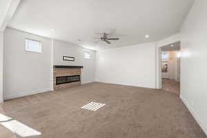 Unfurnished living room with light colored carpet, a brick fireplace, plenty of natural light, and recessed lighting