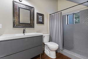 Bathroom featuring a stall shower, vanity, and dark wood-style flooring