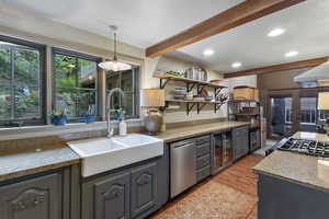 Kitchen with light stone countertops, gray cabinetry, beamed ceiling, stainless steel dishwasher, and wine cooler