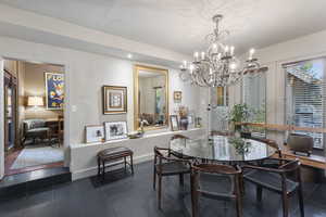 Dining room with dark tile patterned flooring, recessed lighting, and a chandelier