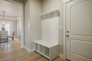 Mudroom with light wood-style flooring, a chandelier, and ornamental molding