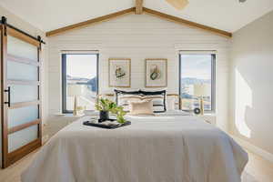 Primary Bedroom with contemporary sliding door, light wood-style floors, wood walls, wood beams, a mountain view, and a ceiling fan