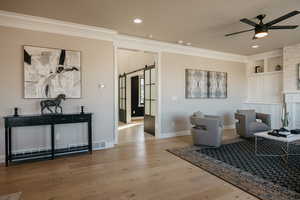 Family Room off of Dining Room w/ Fireplace, Built-in Cabinets, ceiling fan, wood finished floors, crown molding, and recessed lighting