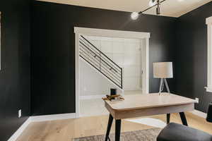 Office featuring access to front entry, custom wood highlight wall, light wood-style floors and baseboards
