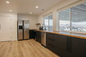 Kitchen with appliances with stainless steel finishes, butcher block counters, recessed lighting, and light wood-style floors