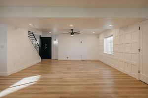 Basement family room with recessed lighting, light wood-type flooring, gun/storage safe, full kitchen, custom woodwork and ceiling fan