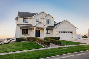 View of front of home featuring board and batten siding, a porch swing, a front lawn, and concrete driveway