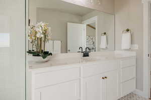 Bathroom with vanity, tiled walk-in shower, and light tile patterned floors