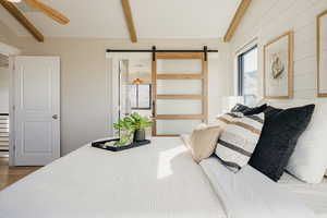 Primary Bedroom featuring contemporary sliding door, wood finished floors, ensuite bath, and ceiling fan