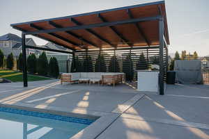 View of pool & covered patio with a ceiling fan and an outdoor kitchen hangout area