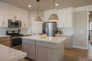 Kitchen featuring appliances with stainless steel finishes, a center island, tasteful backsplash, recessed lighting, quartz countertops and light wood-type flooring