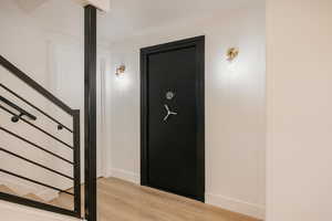Contemporary railing leading to Gun/Storage Safe with shelving.  Hall with wood finished floors and stairs