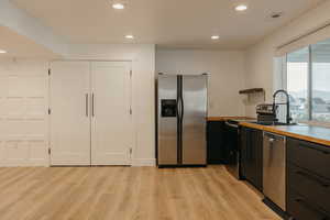 Kitchen featuring appliances with stainless steel finishes, recessed lighting, light wood finished floors, butcher block counters, and open shelves
