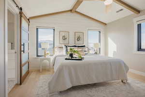 Primary Bedroom featuring light wood-style flooring, multiple windows, wood beams sitting area and a sliding door