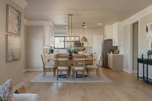 Dining room with light wood-style flooring, ornamental molding, and recessed lighting