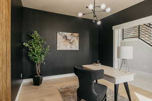 Home office featuring custom wood wall, wood finished floors and a chandelier