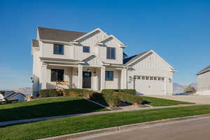 View of front of property with board and batten siding, a porch, a front lawn, and driveway