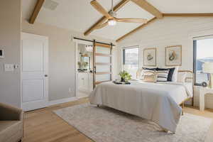 Primary Bedroom featuring contemporary sliding door, light wood-style floors, a ceiling fan, and ensuite bathroom
