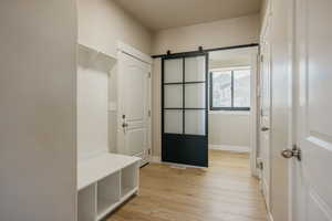 Mudroom featuring access to 1/2 bathroom, contemporary sliding door and light wood-type flooring