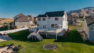 Back of house featuring stairs, a deck with mountain view, a residential view, a trampoline, basketball court and an outdoor fire pit