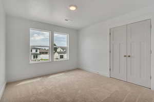 Unfurnished bedroom featuring a closet and light carpet