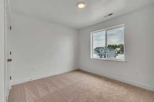 Empty room featuring baseboards and light colored carpet