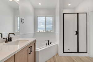 Full bathroom with a bath, vanity, a stall shower, light wood-style floors, and recessed lighting