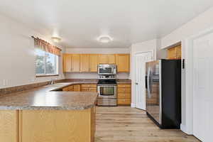 Kitchen with stainless steel appliances, a peninsula, and light wood-style flooring