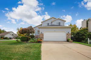 Traditional-style house featuring brick siding, a front lawn, driveway, and a garage