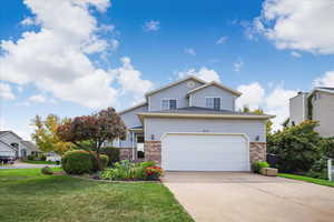 Traditional-style home with brick siding, driveway, a front lawn, and a garage