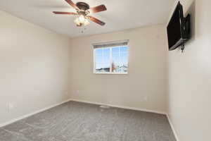 Carpeted spare room with baseboards and a ceiling fan