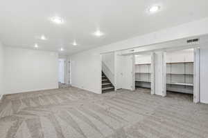 Finished below grade area with stairs, light carpet, a textured ceiling, and recessed lighting