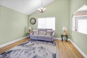 Living area featuring light wood-style floors, a chandelier, and high vaulted ceiling