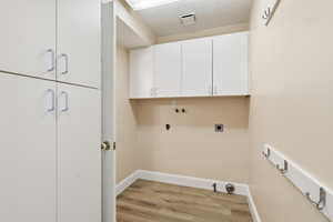Washroom with cabinet space, light wood-style flooring, hookup for a washing machine, gas dryer hookup, and hookup for an electric dryer