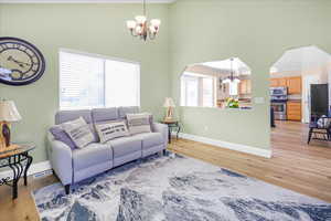 Living room featuring a chandelier, light wood-type flooring, and a high ceiling