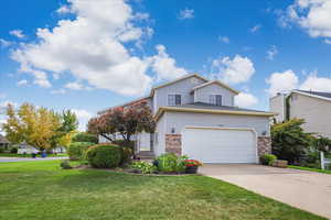 View of front of house featuring brick siding, a front yard, concrete driveway, and an attached garage