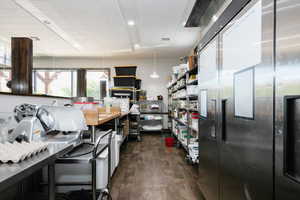Kitchen with stainless steel refrigerator, dark wood finished floors, and decorative light fixtures