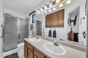 Full bathroom with a shower stall, light tile patterned flooring, and double vanity