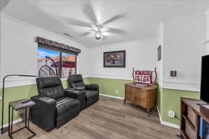 Living area featuring wood finished floors, a textured ceiling, ornamental molding, and ceiling fan