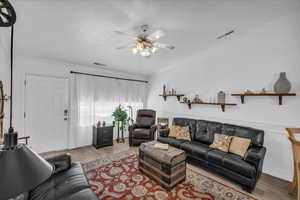 Living area featuring ornamental molding, wood finished floors, ceiling fan, and a textured ceiling